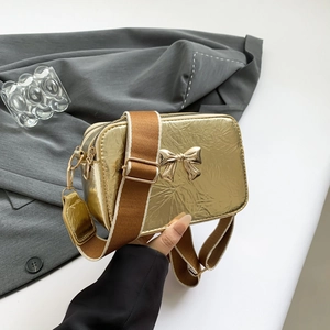 Metallic gold crossbody bag with bow detail and wide fabric shoulder strap