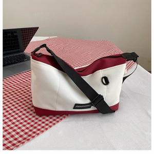 Detail view of red and white canvas crossbody bag with adjustable strap and brand tag