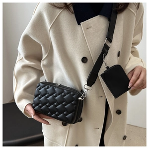 Close-up of black quilted crossbody bag with stylish wide shoulder strap and mini pouch