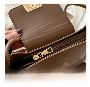 Close-up of smooth gold zipper and magnetic buckle on brown leather shoulder bag