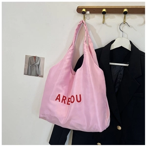 Détail d'un sac cabas en toile rose suspendu à un crochet dans un intérieur minimaliste