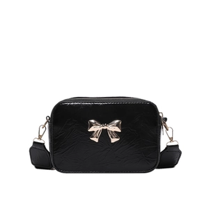 Fashionable black pleated crossbody bag with a gold metal bow and wide shoulder strap