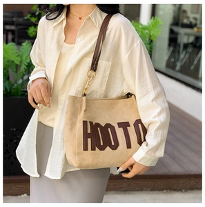 Détail du sac cabas en daim beige avec logo HOOTO en cuir et chaîne dorée élégante