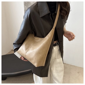 Detail of minimalist beige oversized PU leather hobo bag with soft pleated texture and wide strap