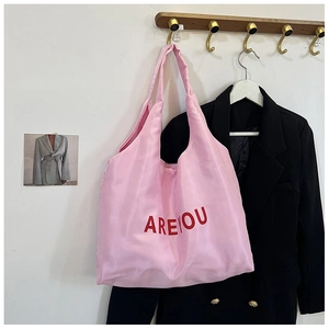 Détail du sac fourre-tout en tissu rose avec lettres AREYOU rouges sur fond épuré