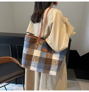 Texture dettagliata di una borsa tote grande in lana a quadri con tracolla in pelle