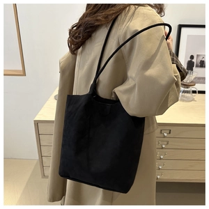 Dettaglio ravvicinato di una borsa tote minimalista in pelle scamosciata nera in casa
