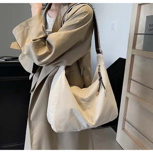 Détail du sac hobo crème avec large bandoulière marron et fermeture éclair à franges
