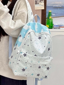 Close-up of a large light blue star print backpack featuring front zipper pocket detail