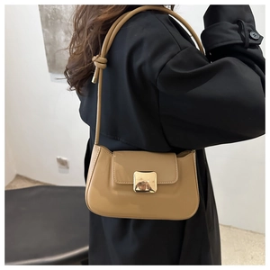 Detail view of khaki baguette bag featuring gold square buckle and knotted strap details