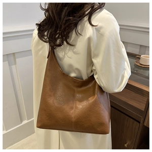 Detail view of caramel brown PU leather hobo shoulder bag shown on model's shoulder