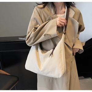 Détail du sac fourre-tout en toile crème avec lanières en cuir marron sur mannequin