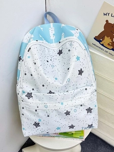 Detail of light blue star print backpack featuring white zipper and top handle strap
