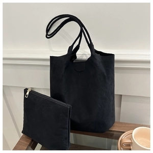 Détail d'un ensemble de sacs seau noirs en daim avec pochette assortie sur table en bois