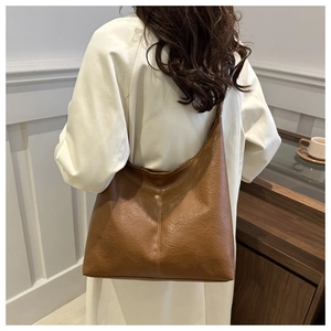 Detailed texture of brown matte leather on a vintage hobo shoulder bag with creases