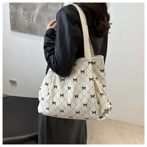 Vista dettagliata della borsa tote in velluto a coste bianco sporco con fiocchi neri