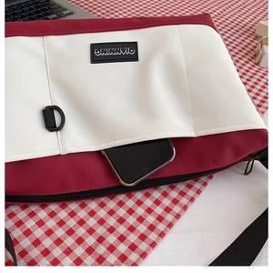 Detailed close-up of a red and white canvas crossbody bag with a phone in the front pocket