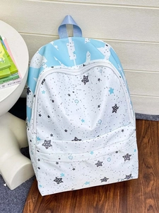 Detailed view of canvas backpack featuring blue star patterns and a front zipper pocket