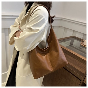 Close-up of brown textured leather hobo tote bag showing vintage PU finish and wide strap