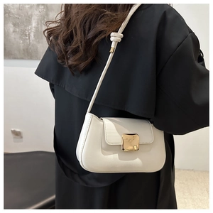 Close-up of a minimalist white shoulder bag featuring a square gold buckle and knot detail