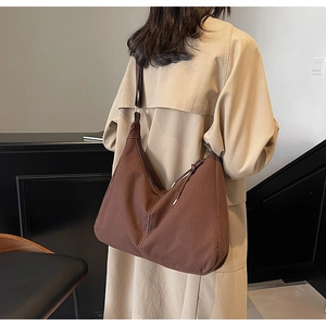 Vue arrière d'un grand sac hobo en toile marron montrant sa forme en croissant porté à l'épaule