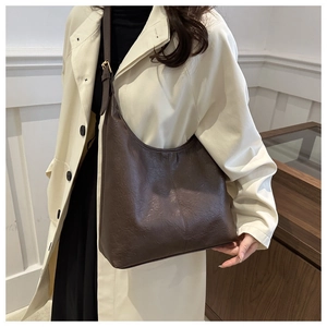Close-up of retro pleated texture on dark brown hobo bag with gold metal buckle