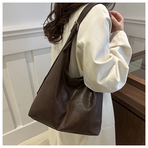 Close-up of textured deep brown leather tote bag with adjustable metal buckle strap