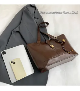 Detail shot of a dark brown retro tote bag showing size comparison with phone and iPad