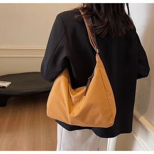 Détail du grand sac cabas en toile marron avec coutures contrastées et bandoulière en cuir