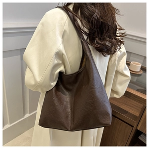 Detail of soft brown leather tote bag with vintage pebble grain texture on shoulder strap