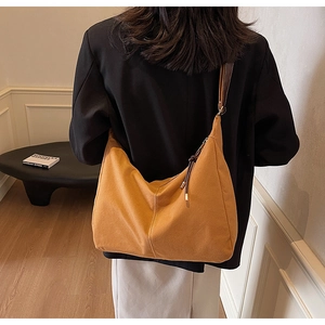 Détail du sac hobo jaune moutarde montrant la texture et la bandoulière en cuir brun