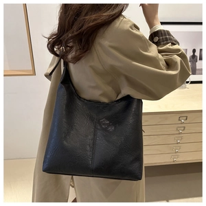 Close-up of black hobo bag with lychee texture and adjustable strap on a female model