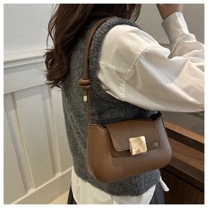 Detail of brown vintage shoulder bag featuring smooth leather and gold metal buckle