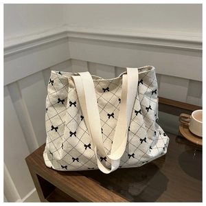 Dettaglio della borsa tote in velluto a coste beige con trama a rombi neri e fiocchetti