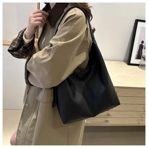 Close-up of black retro tote bag with textured faux leather and wide shoulder straps