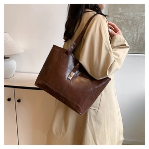 Detail shot of the vintage dark brown leather tote bag showing golden metallic buckle