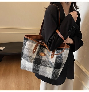 Dettaglio della borsa tote in lana scozzese con manici in pelle e rivetti sulla spalla nera