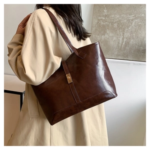 Detailed close-up of dark brown glossy leather tote bag with gold metal twist lock buckle