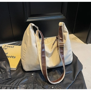 Détail du sac cabas en toile montrant les boucles rétro et les coutures en cuir marron