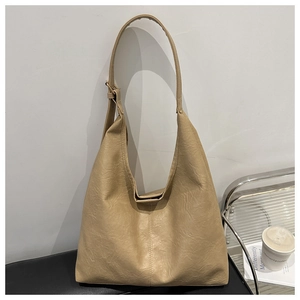Detail of a large beige textured leather hobo bag with an adjustable shoulder strap