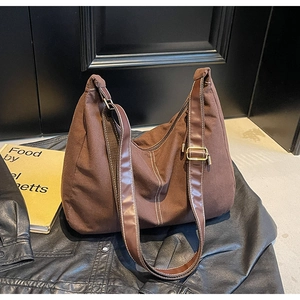 Détail du sac cabas en toile marron avec coutures contrastées et bandoulière en cuir réglable