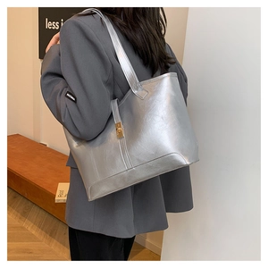 Detail of silver metallic tote bag featuring a gold twist-lock and fine leather texture