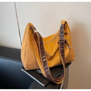 Détail du sac fourre-tout vintage moutarde avec bandoulière en cuir sur canapé style vie