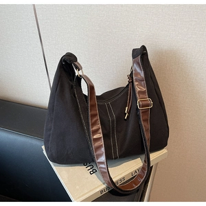 Détail du sac cabas en toile noire avec surpiqûres contrastées et bandoulière en cuir brun