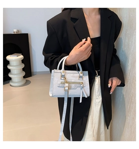 Close-up of a minimalist grey crossbody bag featuring gold hardware and front zipper pocket