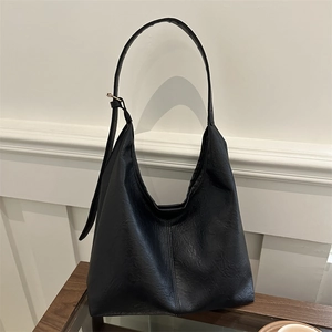 Minimalist black lychee texture leather hobo bag with gold buckle on wooden surface