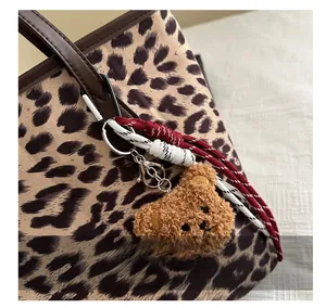 Detail of plush bear bag charm with leopard print tote bag texture and woven cord