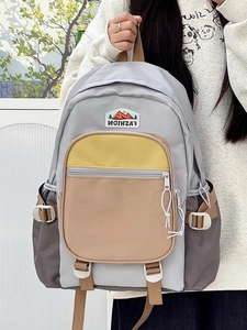 Detail of color-block nylon backpack featuring a vibrant mountain embroidery patch