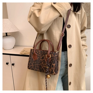 Chic leopard print handbag with brown crossbody strap shown in a stylish room setting