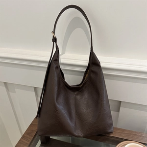Retro dark brown hobo shoulder bag with adjustable strap on a glass wooden table